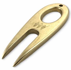Golf divot tool solid brass from front at angle.